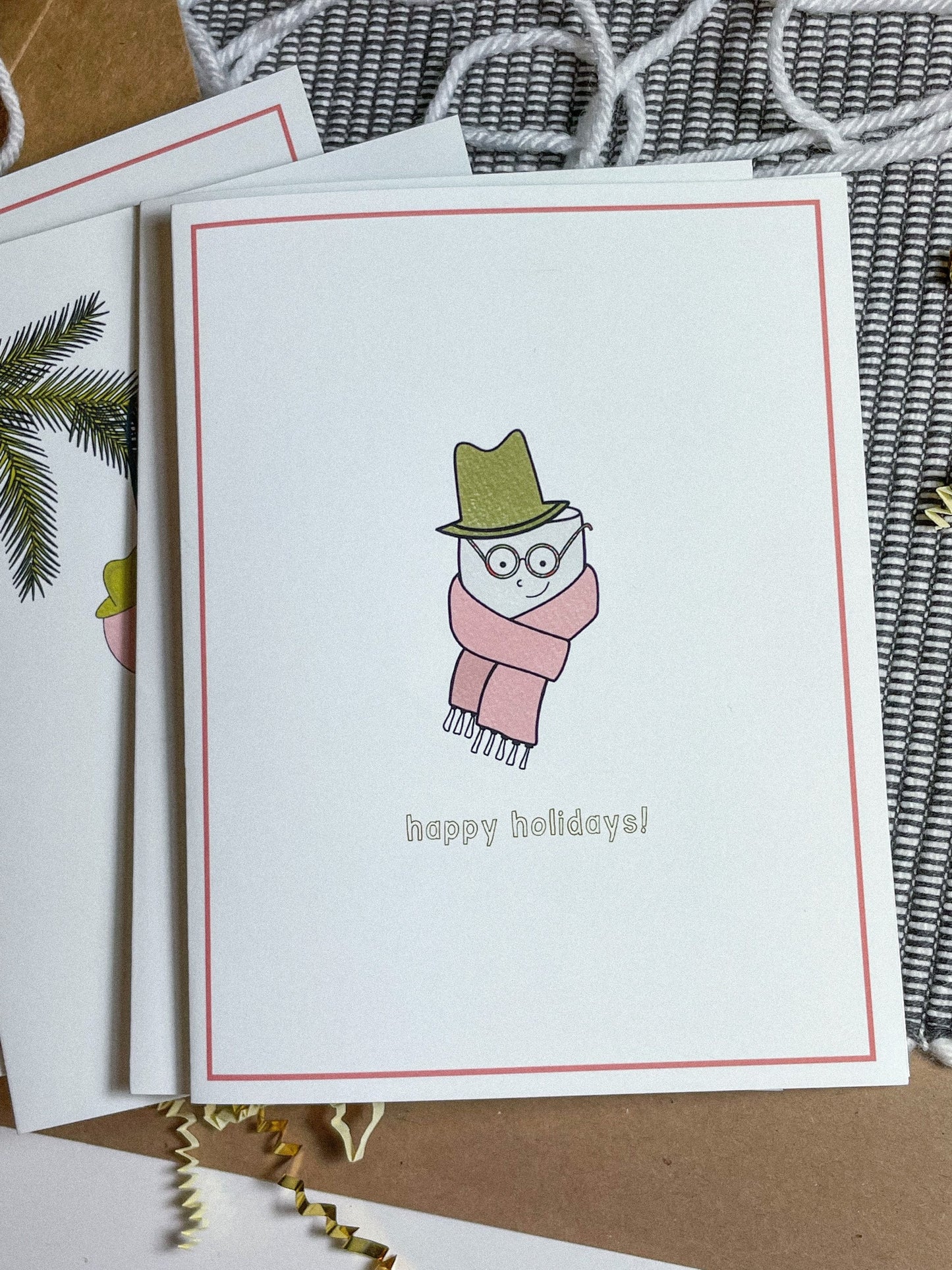 This holiday card features a drawing of a cute little marshmallow man with a scarf and a top hat with the text 'happy holidays!"
