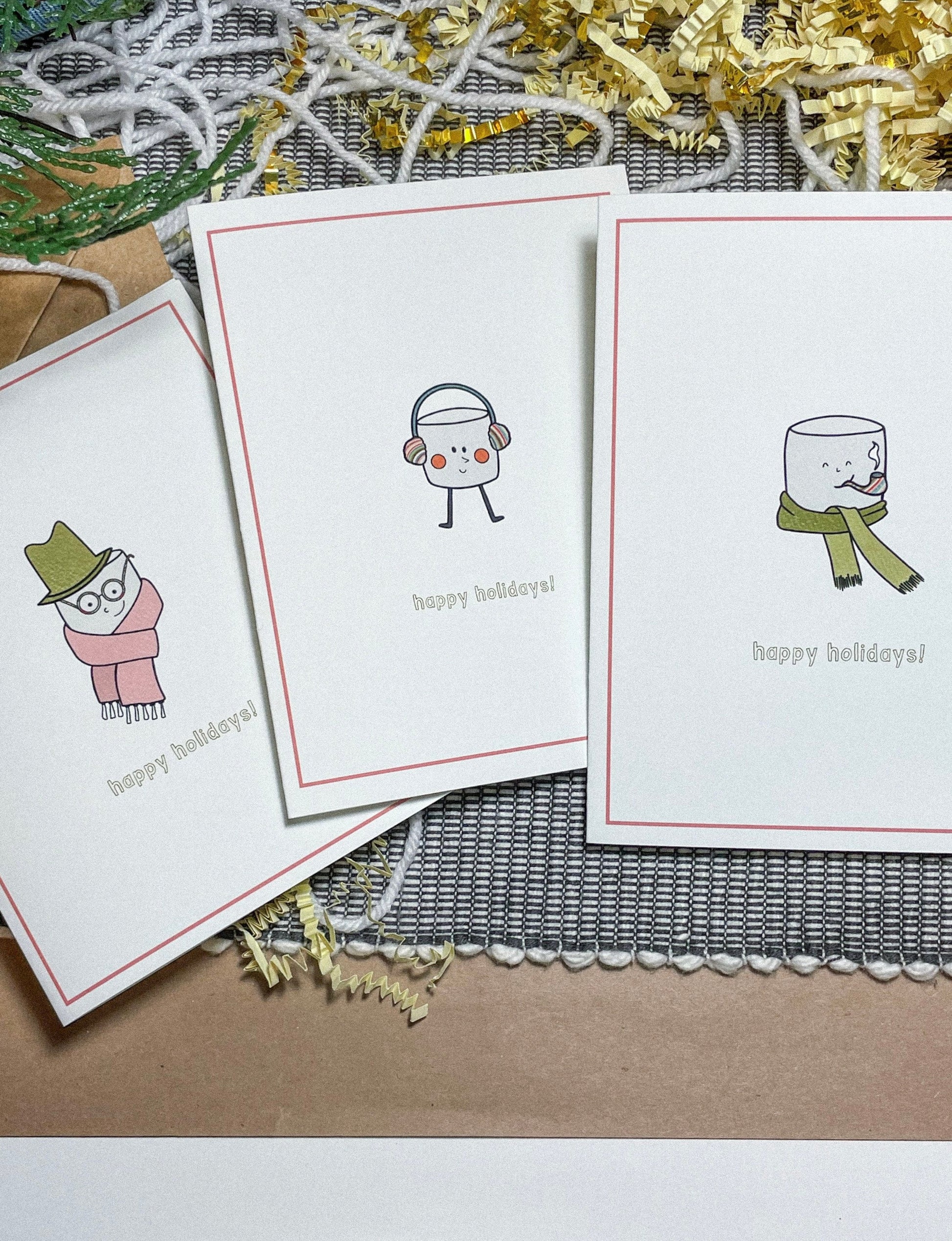 This holiday card features a drawing of a cute little marshmallow man with a scarf and a top hat with the text 'happy holidays!" This shows all 3 of the separate Marshmallow people cards - they are just too cute!