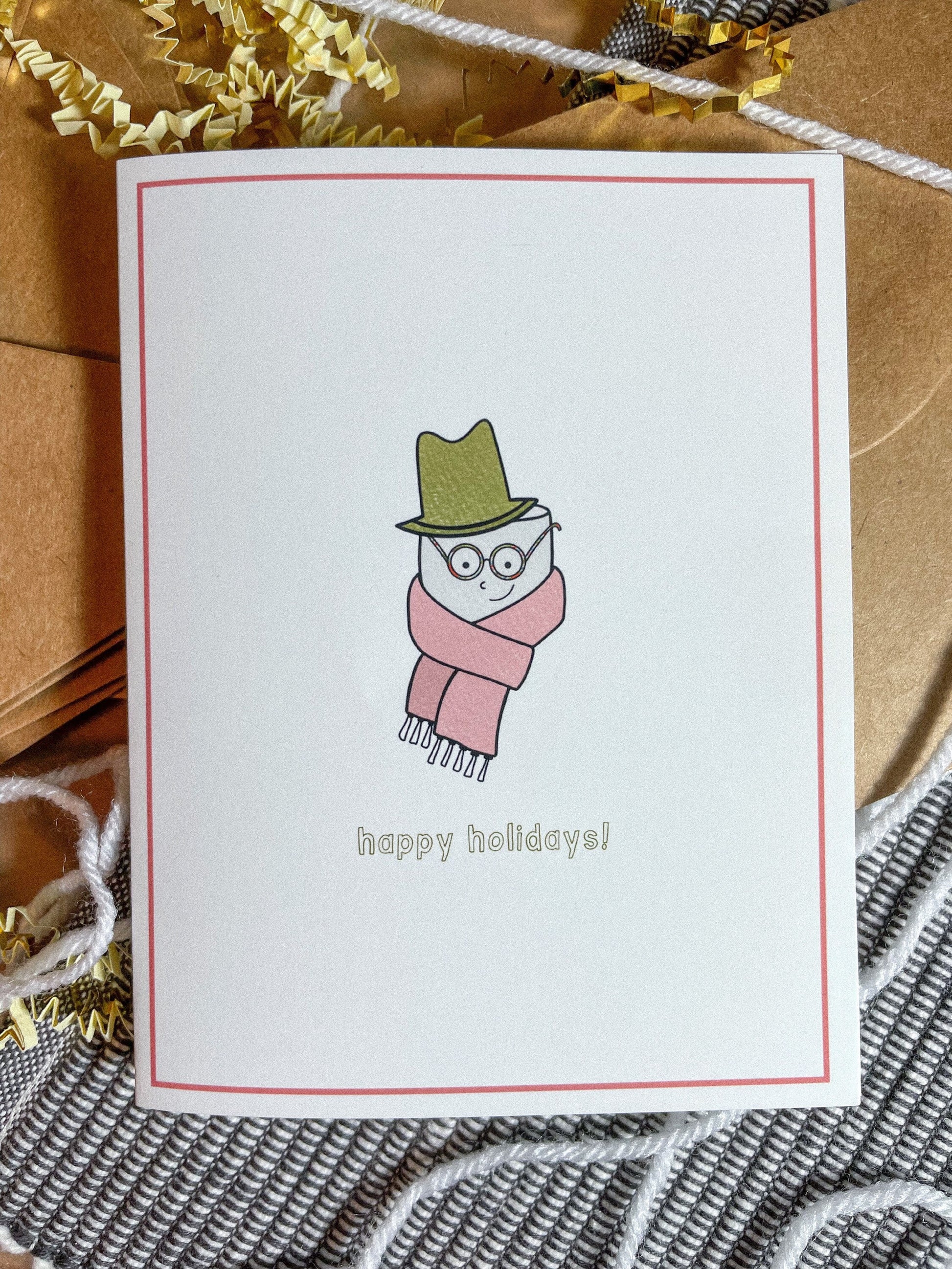 This holiday card features a drawing of a cute little marshmallow man with a scarf and a top hat with the text 'happy holidays!"